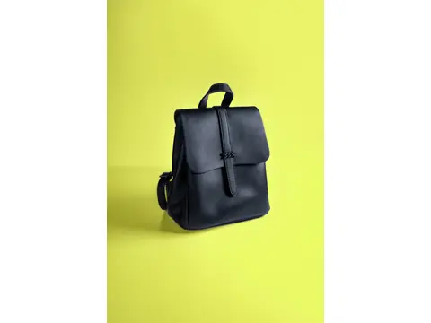 A black backpack against a yellow background